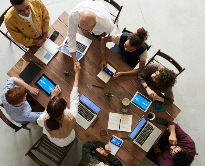 borgen en verbeteren beter bedrijf Team in overleg aan een tafel met laptops, van bovenaf gezien